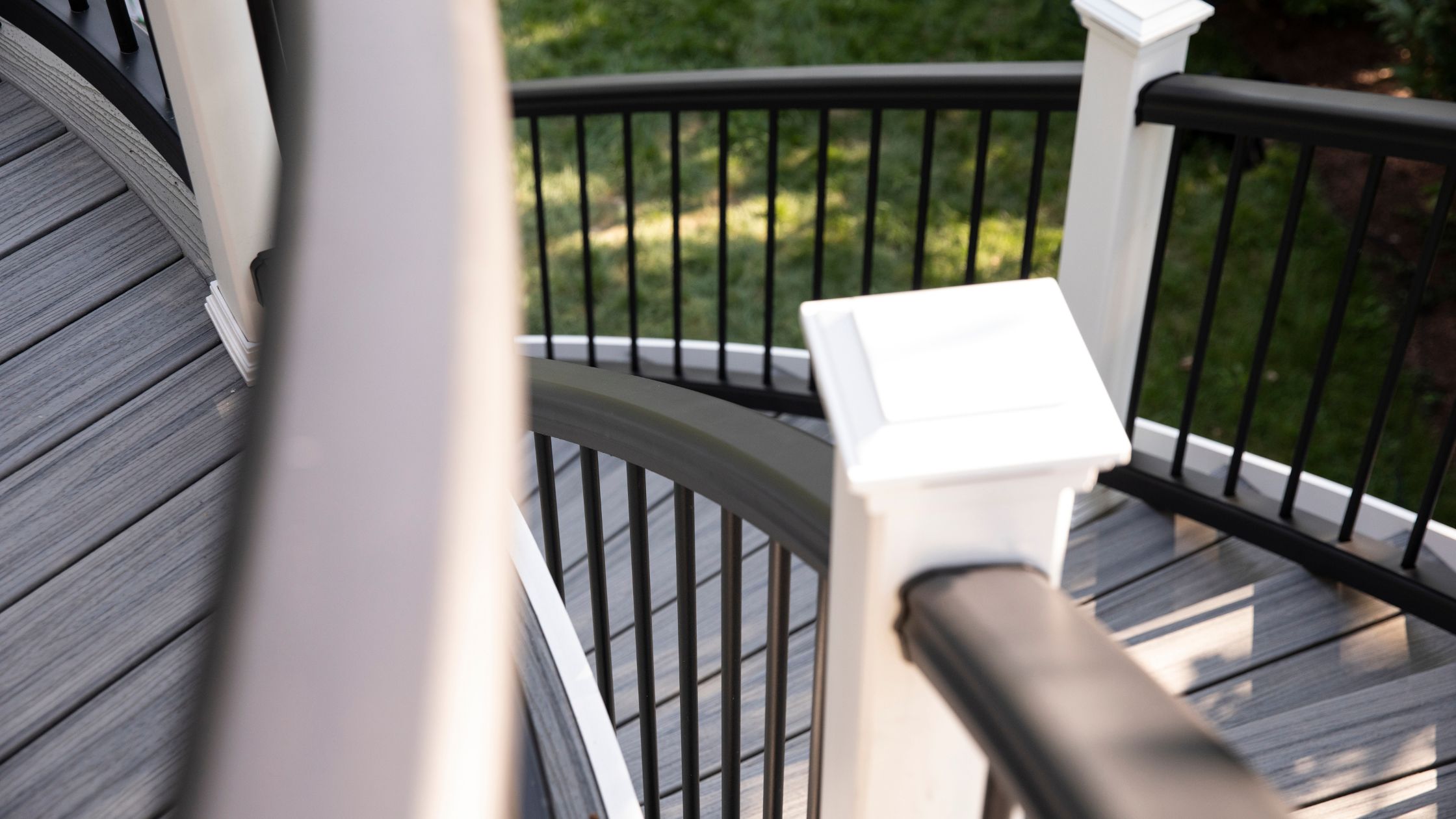 Trex Transcend curved railing in black and white composite shown on a staircase with gray composite decking.
