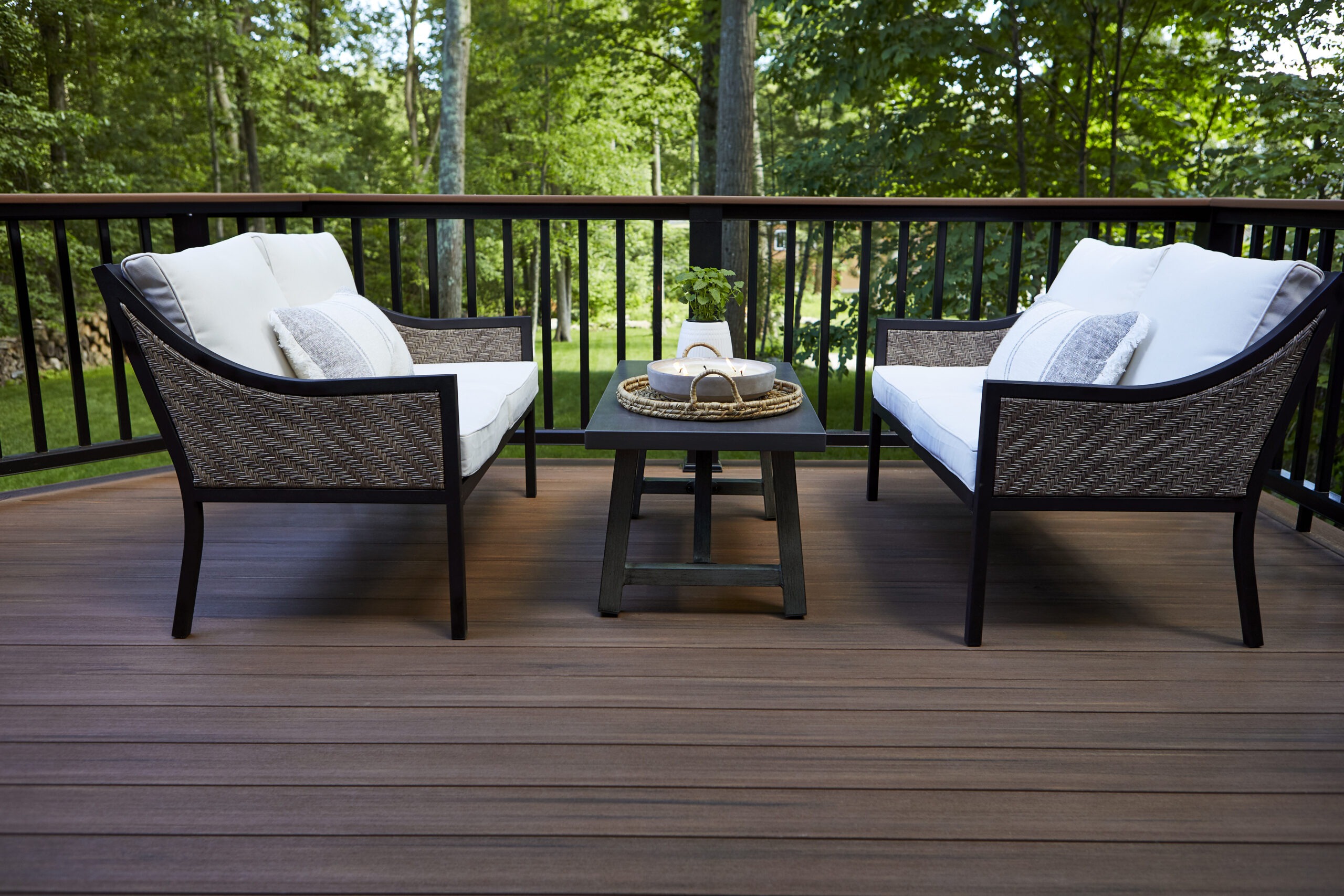 A cozy outdoor deck featuring TimberTech Vintage Mahogany decking, paired with black metal railing and elegant patio furniture, creating a warm and inviting space for relaxation.