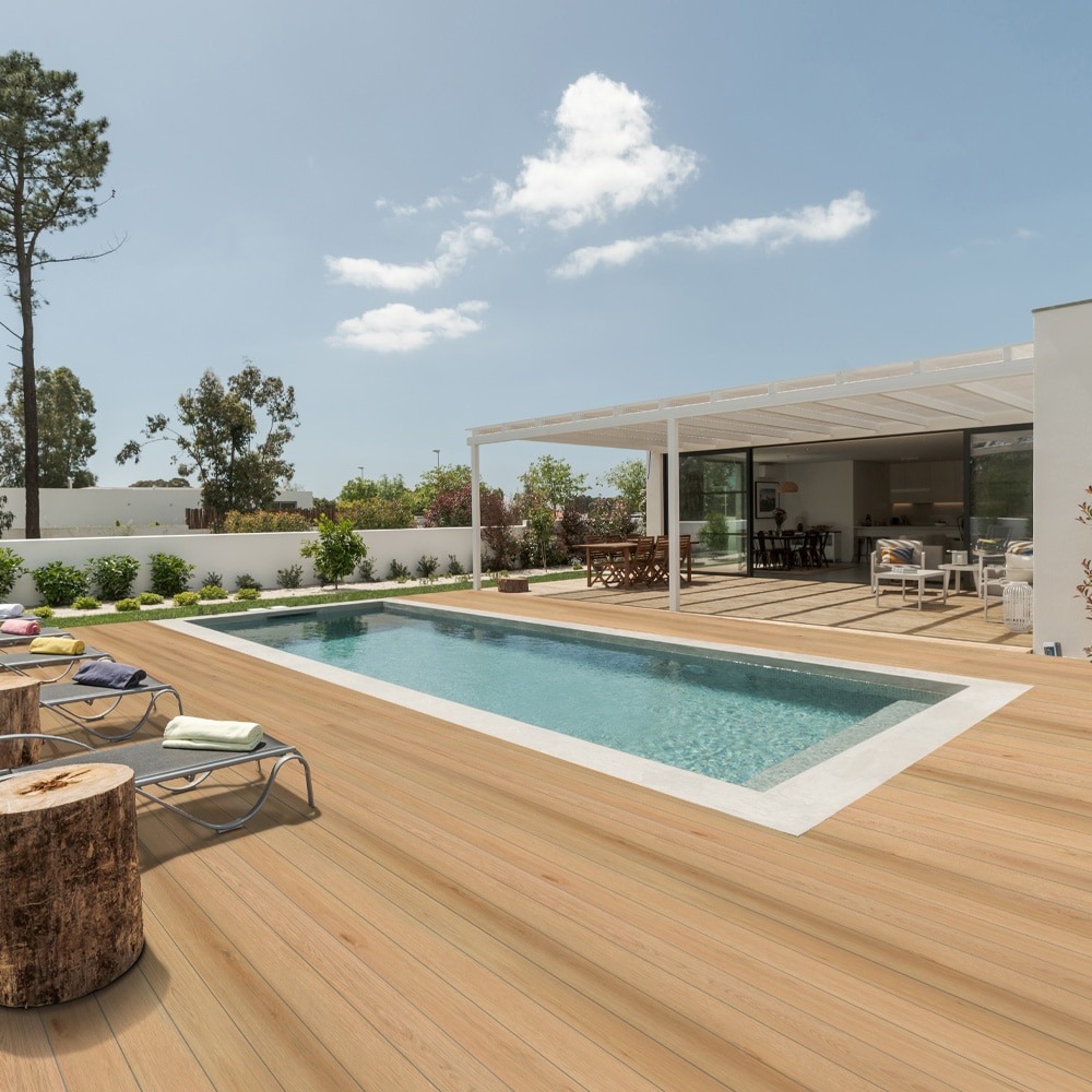 Outdoor pool area finished with Eva-Last Pioneer decking in Barrel Oak, showcasing its soft golden-brown tones and authentic woodgrain texture under direct sunlight, creating a warm, coastal-inspired setting.