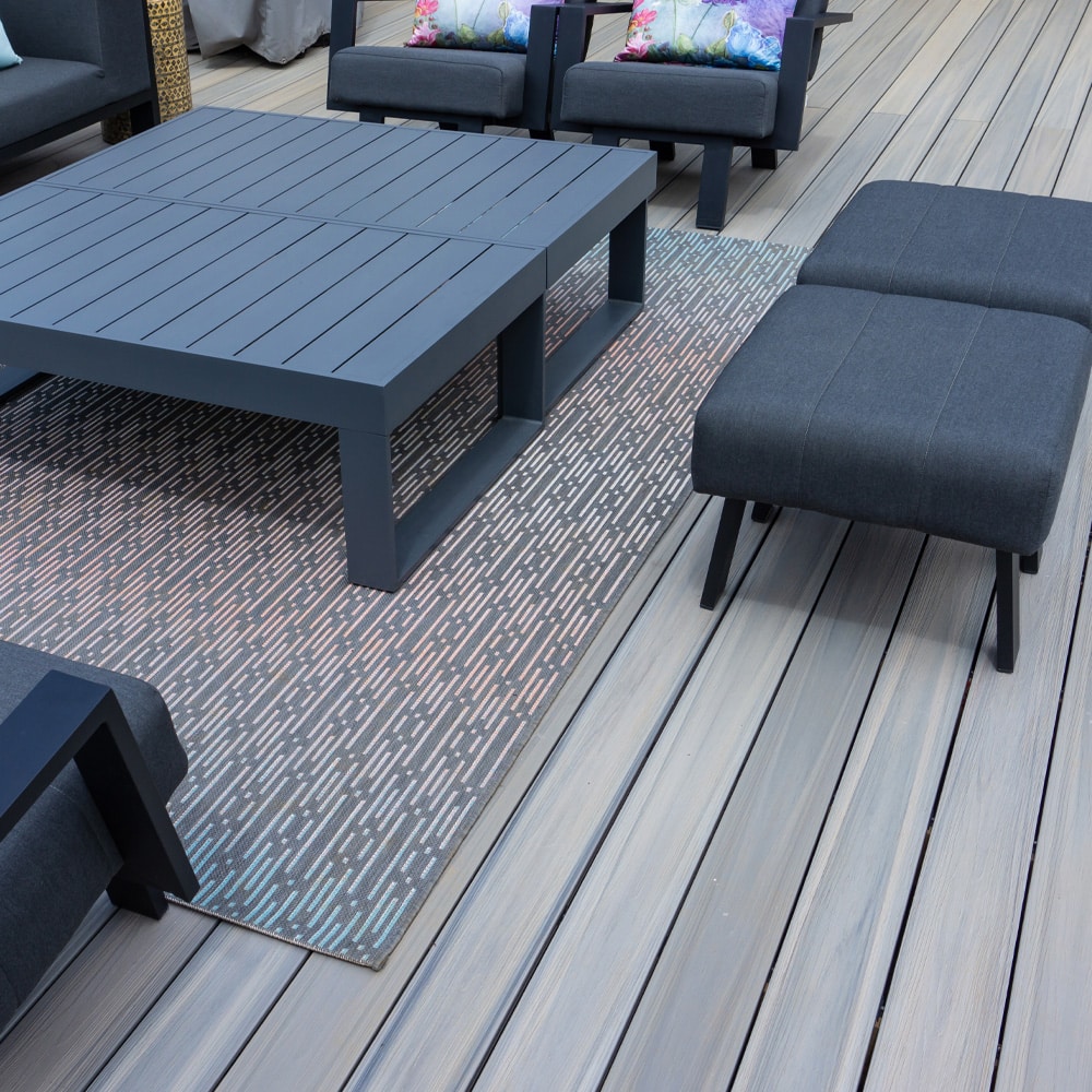 Modern outdoor seating area on Eva-Last Infinity IS Caribbean Coral decking with wide grooved boards and dark gray furniture.