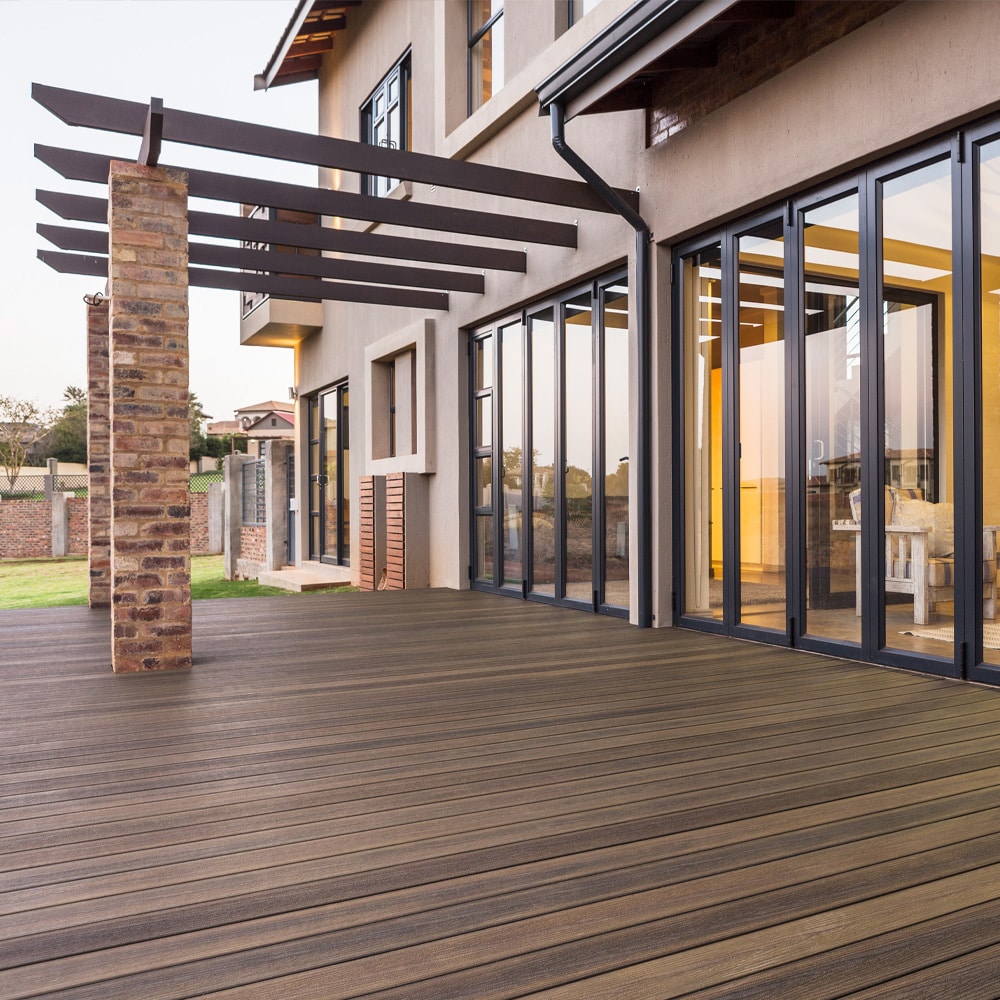 Modern home with sliding glass doors opening to an expansive deck built with Oasis Palm boards in soft brown hues.