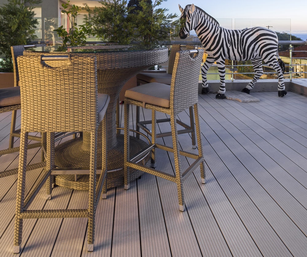 Eva-Last Xavia WYDE decking used on a rooftop patio with wicker bar seating and a life-sized zebra sculpture in the background.