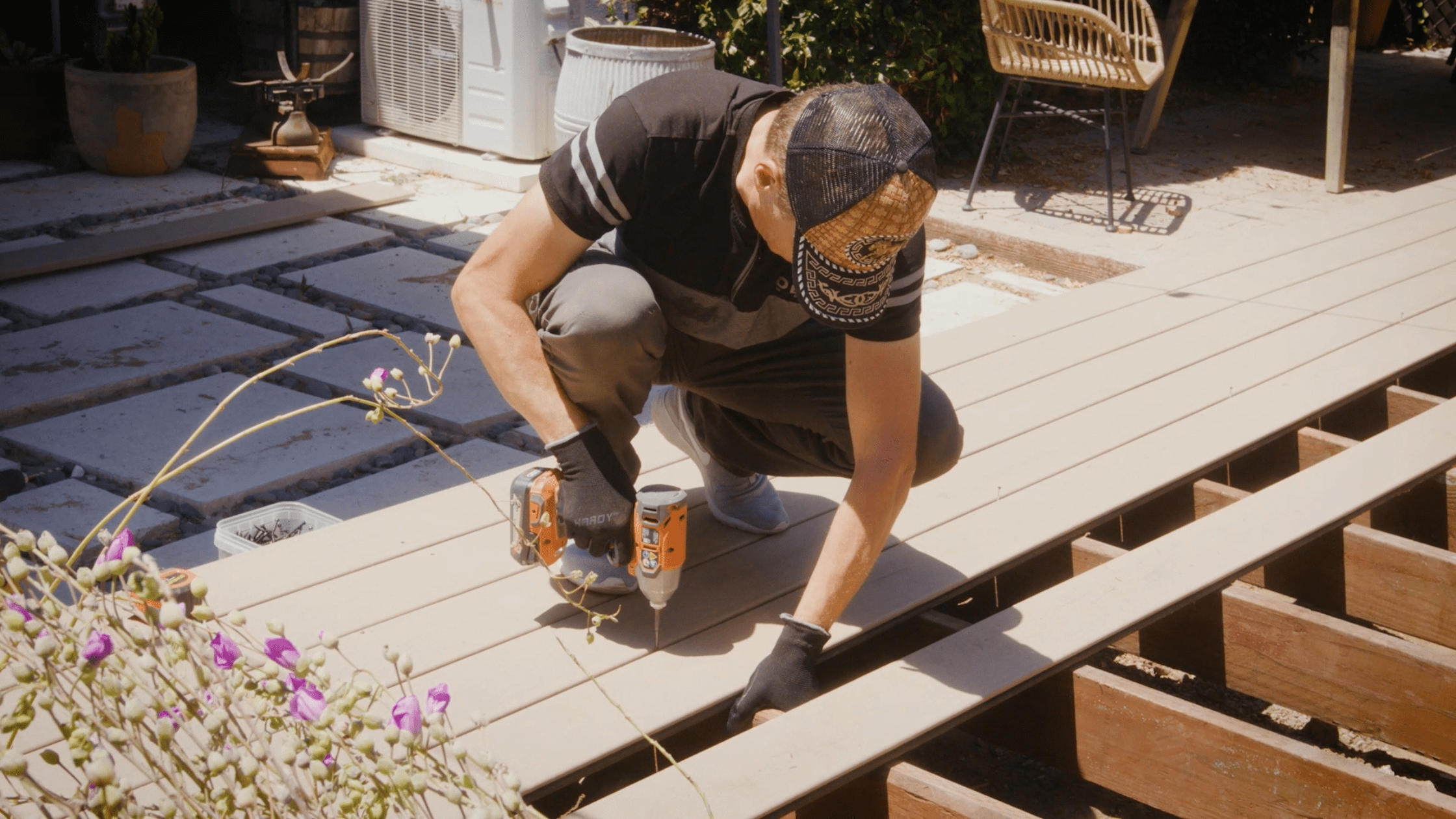 Homeowner replacing surface boards with a drill on an existing deck, showing how much is a deck replacement.