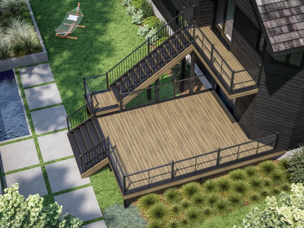 Aerial view of a multi-level deck framed with Deckorators Dark Slate boards. The frame outlines natural-tone deck boards and stair treads, creating contrast against a dark modern house and surrounding lush landscaping.