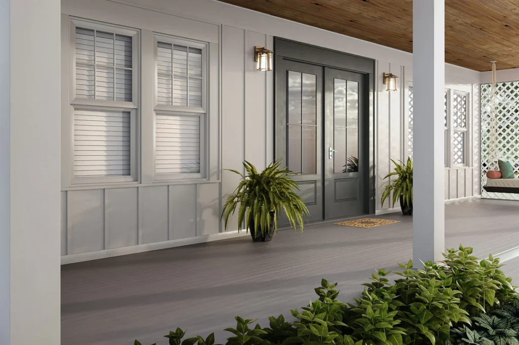 Front porch featuring Deckorators Porch Flooring in Kettle Gray, styled with black double doors, white board-and-batten siding, and potted ferns for a clean and welcoming entryway.