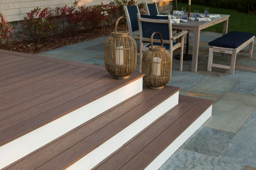 Close-up of Deckorators Vault Mesquite decking used on outdoor stairs, styled with white trim and decorative lanterns for a warm, welcoming entry.