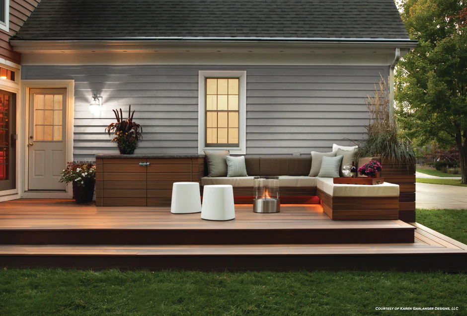 A modern deck with rich brown composite decking, built-in bench seating with neutral cushions, and accent lighting for an upscale outdoor ambiance.
