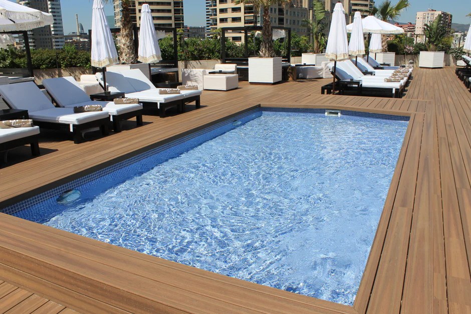 Rooftop pool deck finished in Fiberon Paramount Brownstone, surrounded by white loungers and umbrellas for a resort-style atmosphere with a warm, inviting tone.