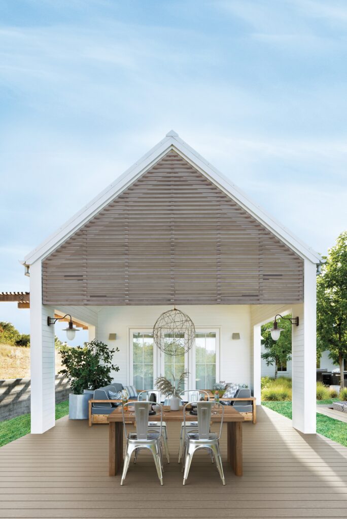 Outdoor dining pavilion with Fiberon Promenade in Shaded Cay, styled with a rustic wooden table, industrial metal chairs, and soft gray decking to complete a breezy backyard setting.