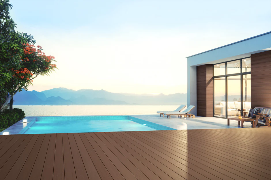 Poolside terrace finished with Russet Dune decking from the Promenade collection, surrounded by contemporary architecture and lounge furniture under the glow of sunrise.