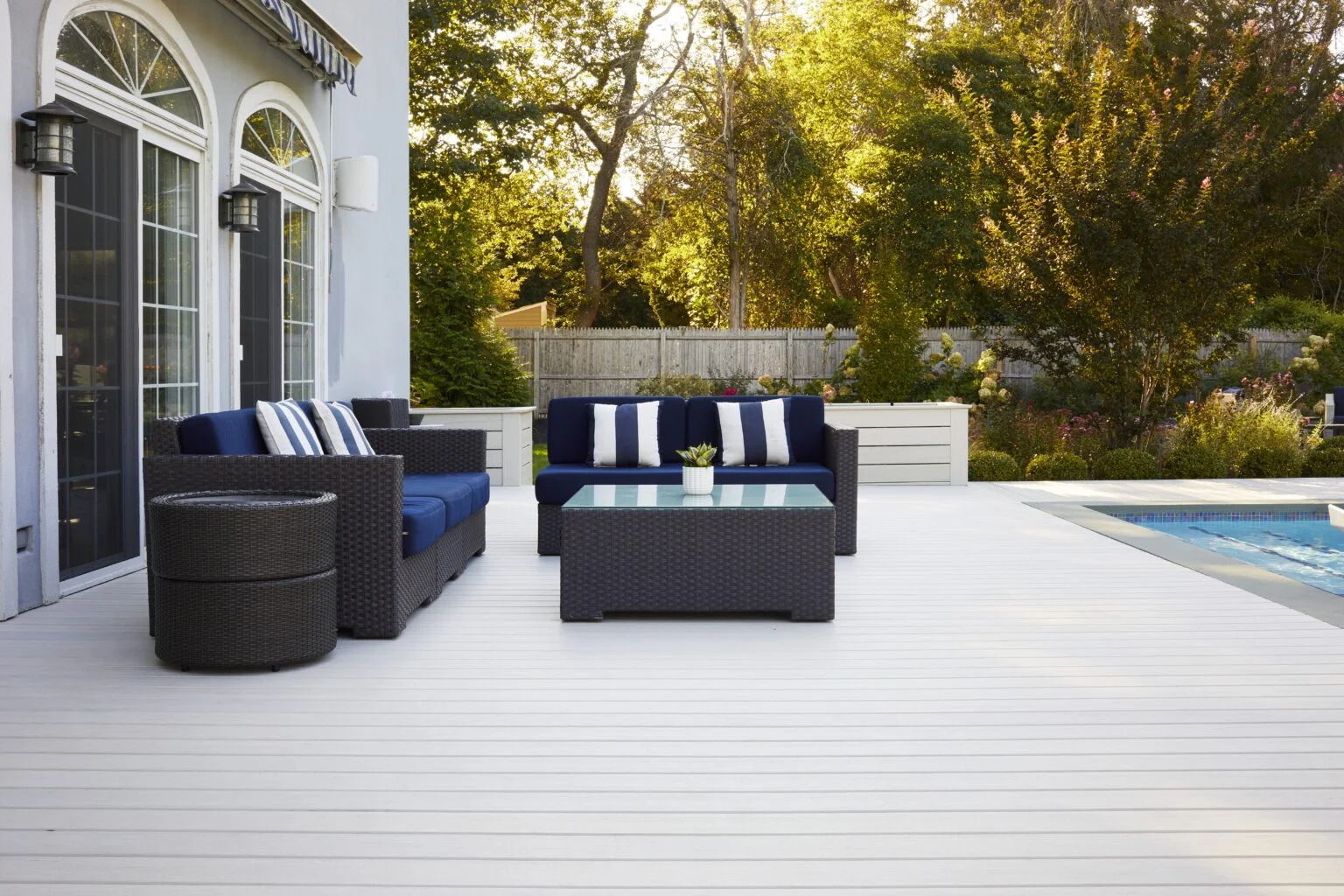 Backyard patio with TimberTech Legacy Whitewash Cedar composite decking, poolside seating, and modern outdoor furniture showing how to install TimberTech decking for a bright, coastal-inspired look.