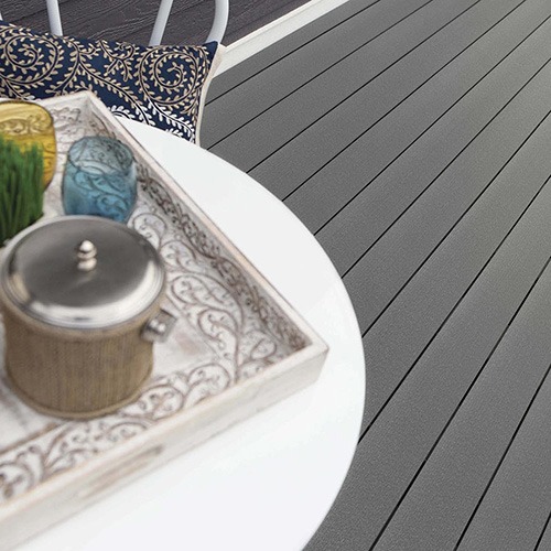 Medium gray composite decking with a smooth matte finish, styled with a white table and decorative tray for a clean, modern outdoor look.