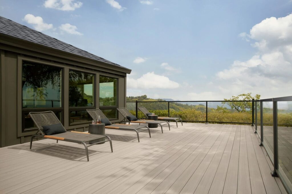 Modern rooftop patio with TimberTech Vintage Coastline™ decking, clean glass railing, and sleek lounge chairs—offering a sophisticated, low-maintenance space with sweeping views.