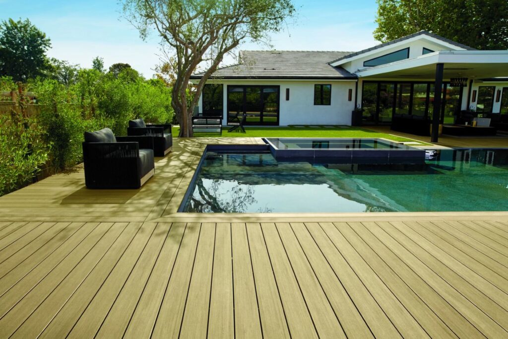 TimberTech Vintage Weathered Teak decking surrounding a sleek backyard pool, with modern black lounge chairs and lush green landscaping creating a resort-style oasis.