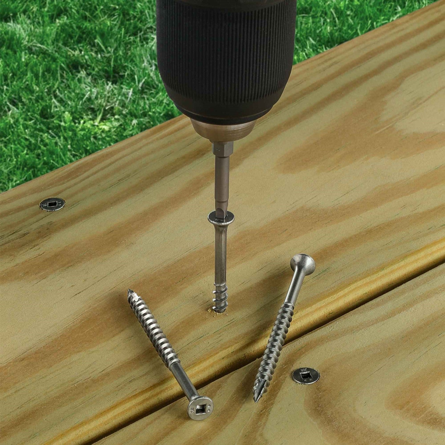 A drill installs deck wood screws into treated lumber, fastening deck boards to the joists with secure holding power.