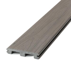 Deckorators Distressed Cherrywood slotted deck board shown in angled close-up. The reddish-brown composite surface includes subtle black undertones and a convincingly realistic woodgrain texture that resembles hand-finished cherry lumber. The groove along the side edge supports hidden fasteners for a sleek, nail-free installation. The board's design blends warmth and authenticity with long-lasting, weather-resistant performance.