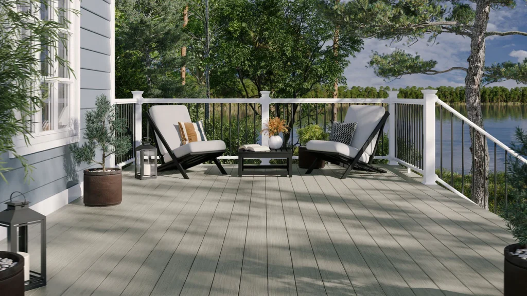 Lakeside deck built with Summit Glacier boards featuring white railing, black balusters, and modern lounge seating. The light greige tone contrasts beautifully with greenery and water views.