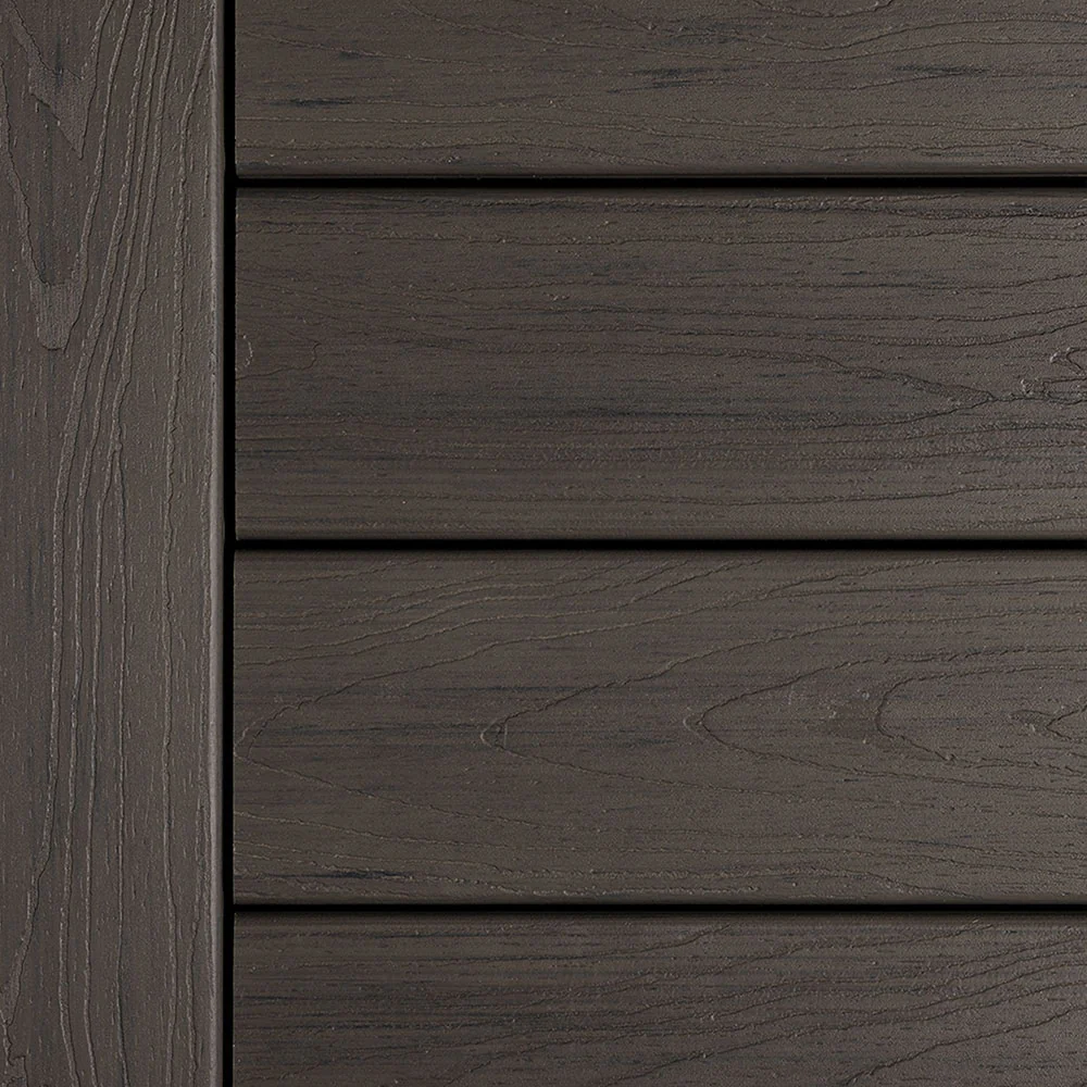 Deckorators Tropics Decking in Tidal Gray displayed in a detailed swatch photo. The composite boards feature cool gray undertones and woodgrain texture, offering the look of weathered hardwood with low maintenance. The clean edge lines and dark charcoal variation create a modern, sophisticated feel.