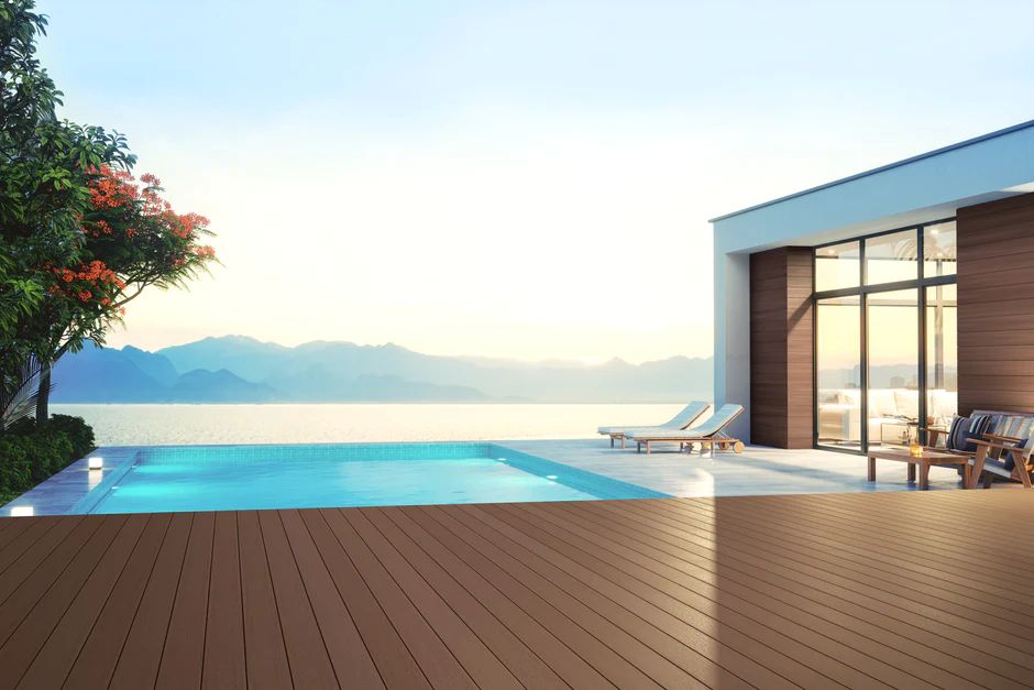 A modern outdoor space featuring rich brown PVC decking boards surrounding a sleek pool with lounge chairs. The durable PVC decking material resists color fading, creating a perfect outdoor retreat for families who want both beauty and low maintenance.