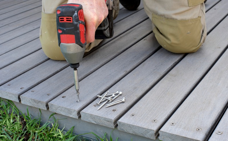 A power drill drives stainless steel screws into wood decking, showing corrosion-resistant fasteners built for long-lasting outdoor projects.