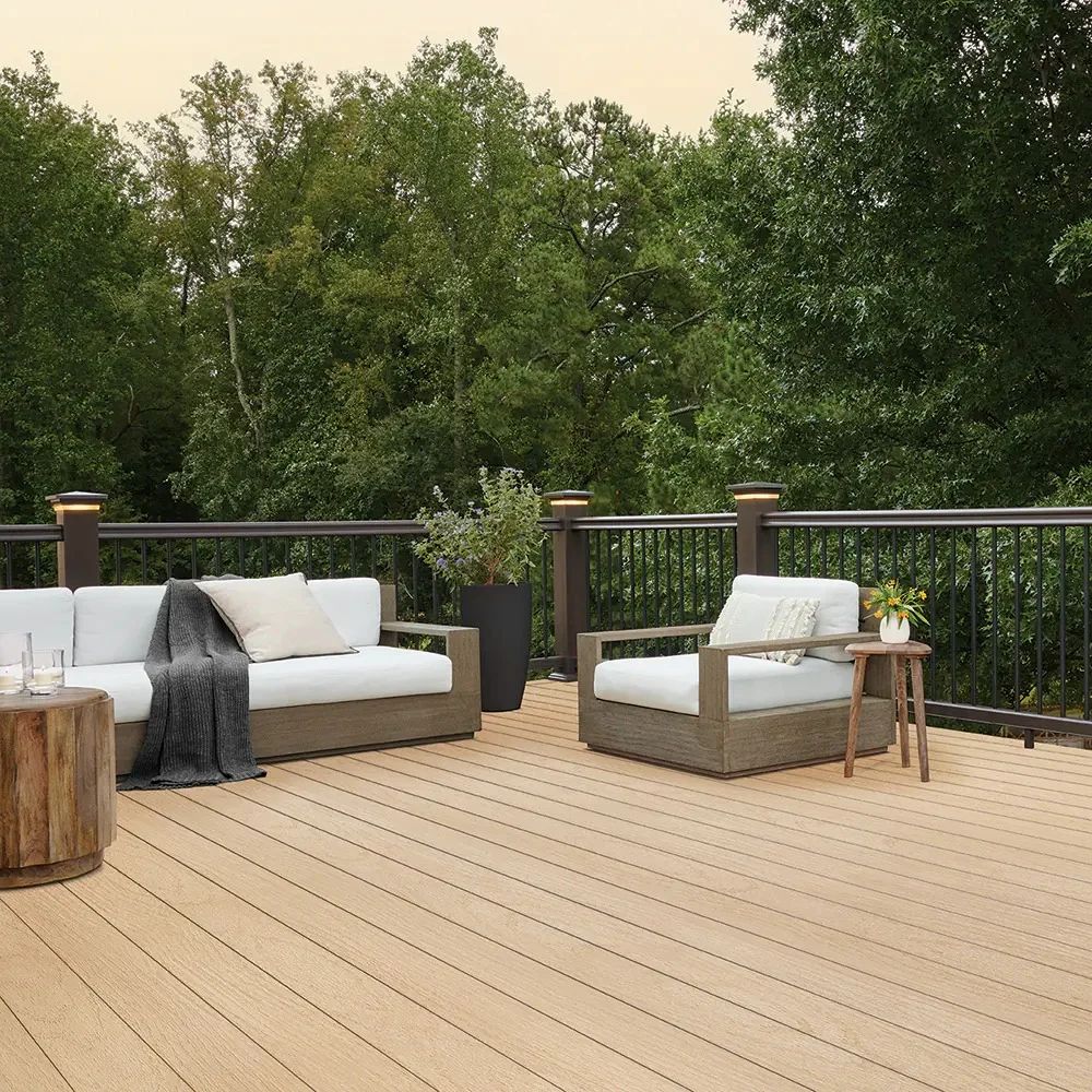 An inviting outdoor lounge built with tan PVC decking boards surrounded by lush greenery. The boards resist color fading and provide a low-maintenance surface that supports both relaxation and entertaining.