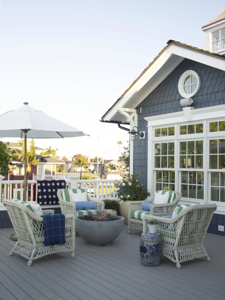TimberTech Harvest Slate Gray deck boards create a crisp contrast against blue shingle siding, styled with light wicker patio seating and patriotic accents.