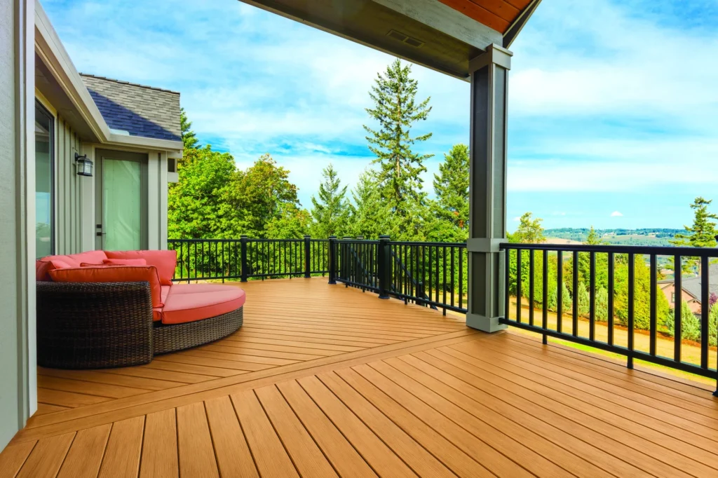 Covered porch built with TimberTech Prime+ Coconut Husk composite decking. The golden oak-inspired tone contrasts beautifully with the black railing and neutral exterior, creating a welcoming space enhanced by the deck’s warm color and low-gloss texture.