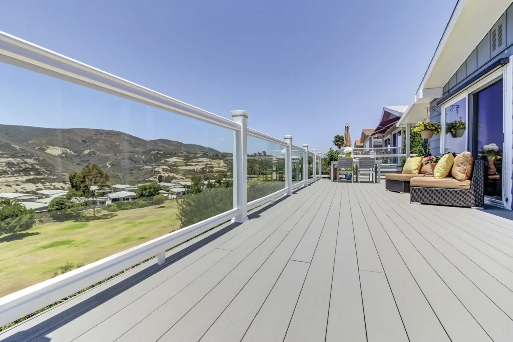 Expansive elevated TimberTech Terrain Stone Ash composite deck with panoramic views, white glass railings, and soft gray boards that mimic weathered wood tones.