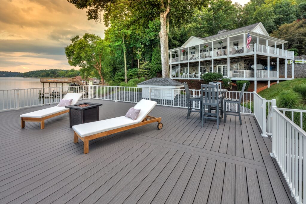 Lakeside deck with Trex Signature Whidbey composite decking, white railing, and sun loungers overlooking dock and trees.