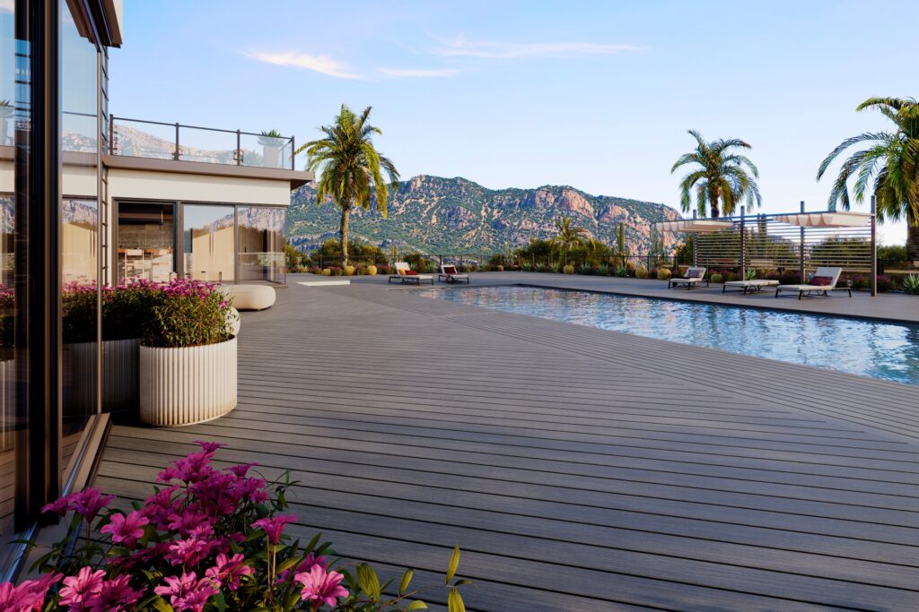 Modern poolside patio with Trex Signature Whidbey composite decking, surrounded by palm trees and mountain views.
