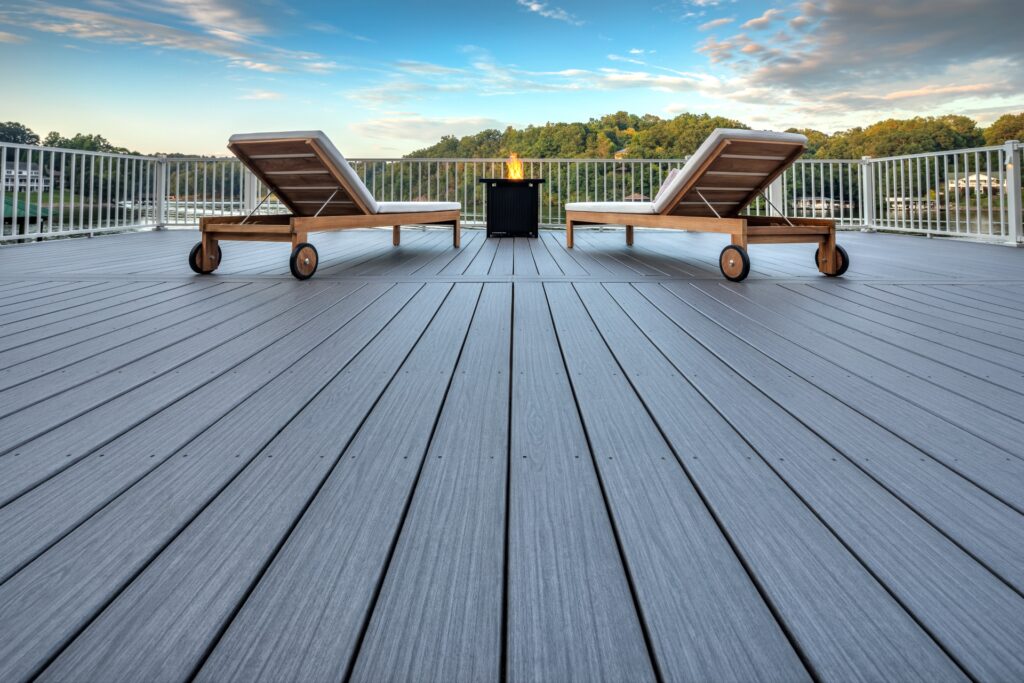 Close-up view of Trex Signature Whidbey composite deck boards with lounge chairs and fire pit on lakeside deck.