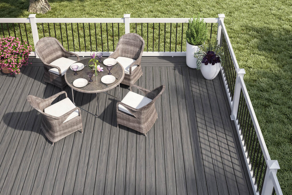 Modern lakefront deck with Deckorators Tropics Hana Brown decking and black railings, styled with white outdoor furniture and a scenic view of the water.
