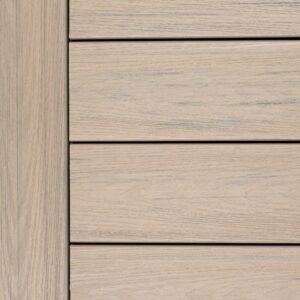 Close-up swatch of Deckorators Venture Shoreline decking showing a light sandy beige tone with soft gray woodgrain streaks and a natural, sun-washed appearance.