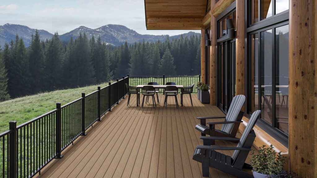 Close-up view of a mountain cabin deck built with Deckorators Altitude Highland decking, featuring black railing, Adirondack chairs, and forest mountain scenery in the background.