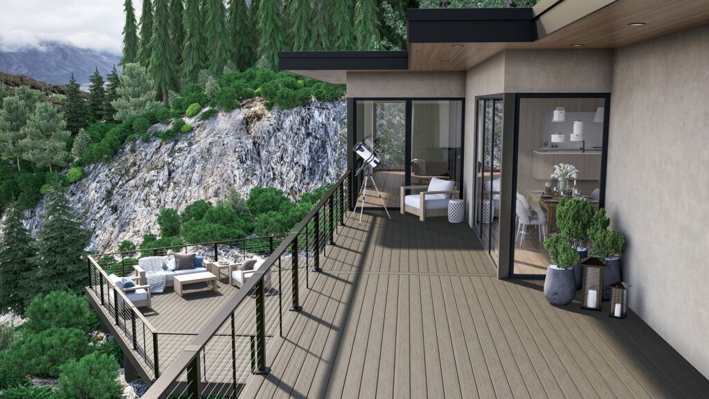 Modern hillside home with an elevated deck built using Deckorators Altitude Trailstone decking, featuring black cable railing, outdoor lounge seating, and forest and mountain views in the background.