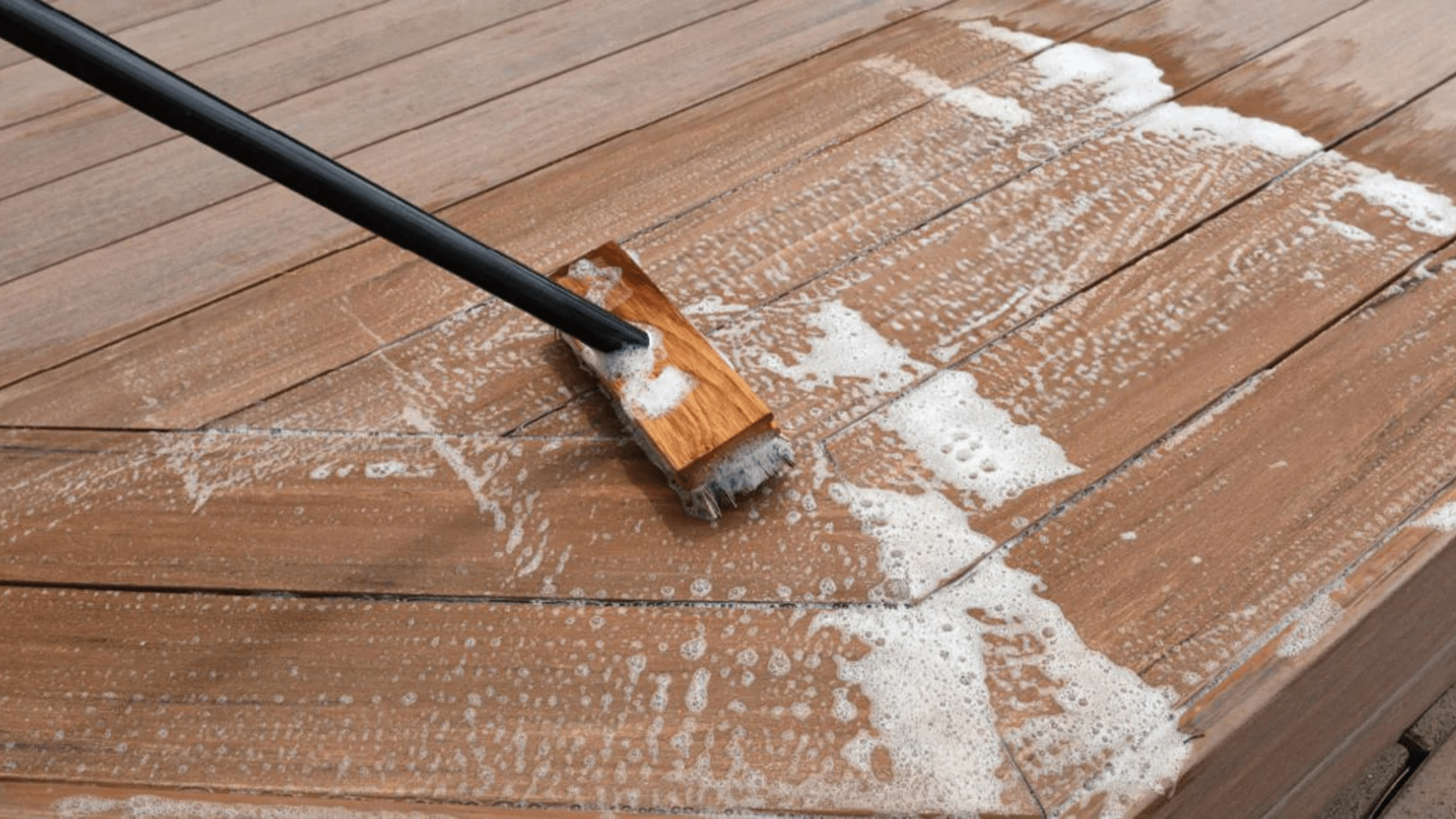 Close-up of a TimberTech composite deck being scrubbed with soapy water and a soft brush, showing the correct method for how to clean TimberTech decking safely.
