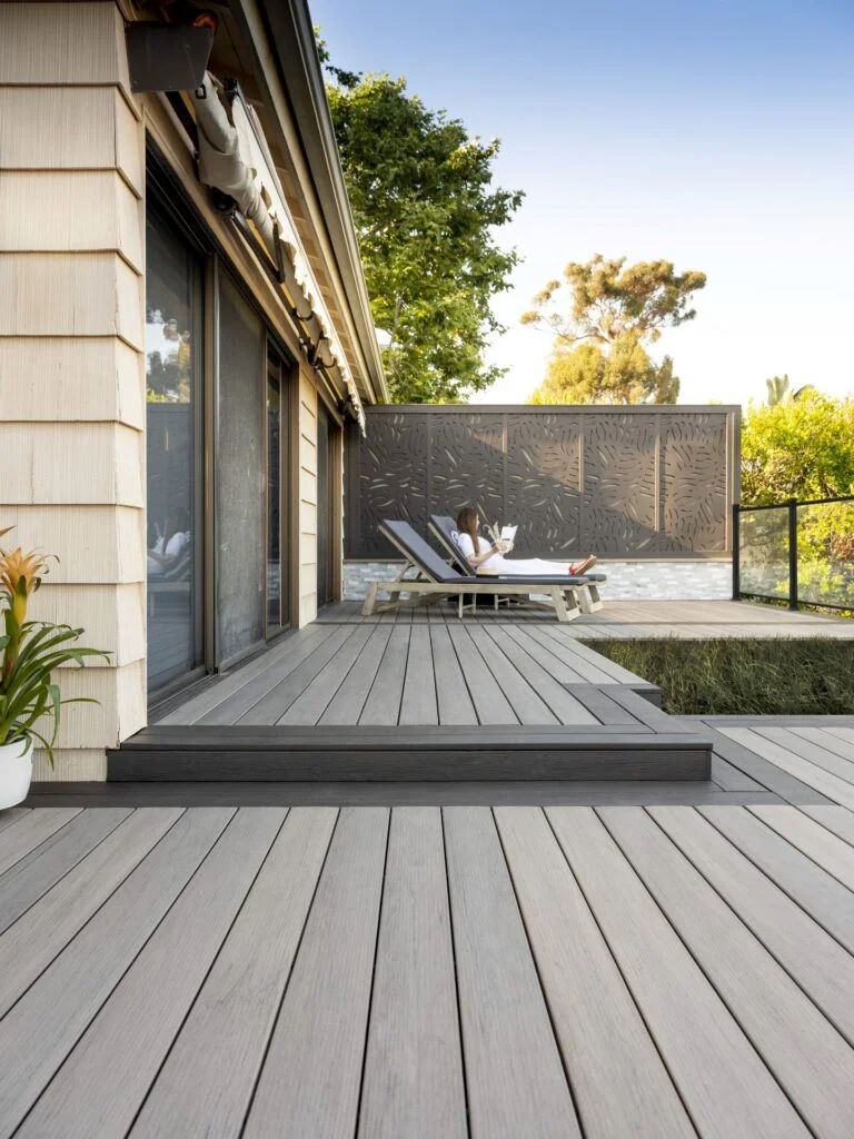 Modern beige home with TimberTech Legacy Ashwood composite decking featuring gray-brown streaks and rich wood-grain texture. The tone adds warmth and depth to the light siding, creating a stylish and natural deck color for beige house designs.