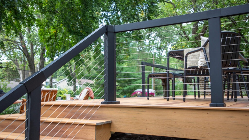 Closeup of black aluminum posts with horizontal cable deck railing on composite deck.