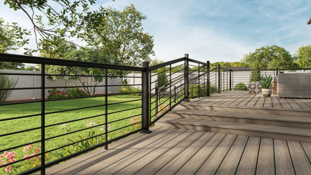 Black aluminum horizontal deck and stair railing with composite decking in backyard.