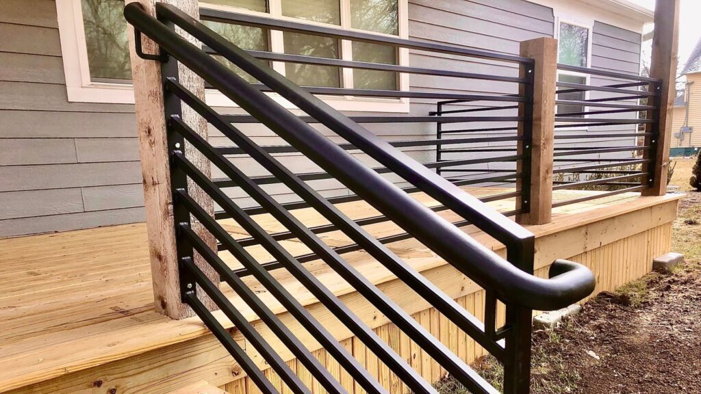 Black horizontal metal stair railing with rustic wood posts and natural deck stairs.