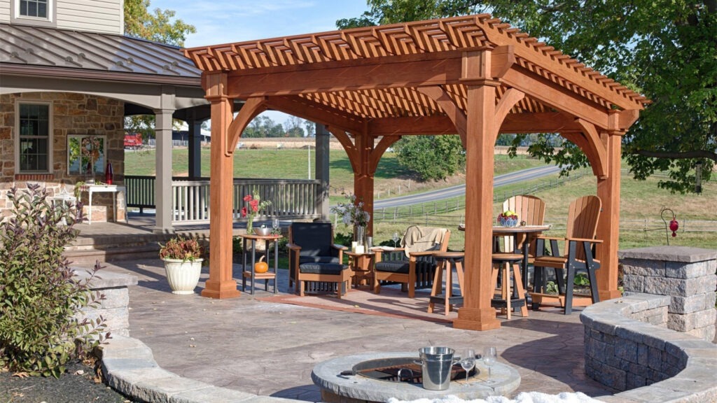 Cedar pergola with lounge seating, firepit area, and stone patio near traditional home.