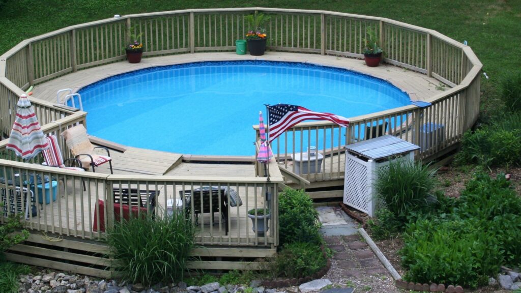 Circular pool deck with American flag, lounge chairs, and patio umbrellas.