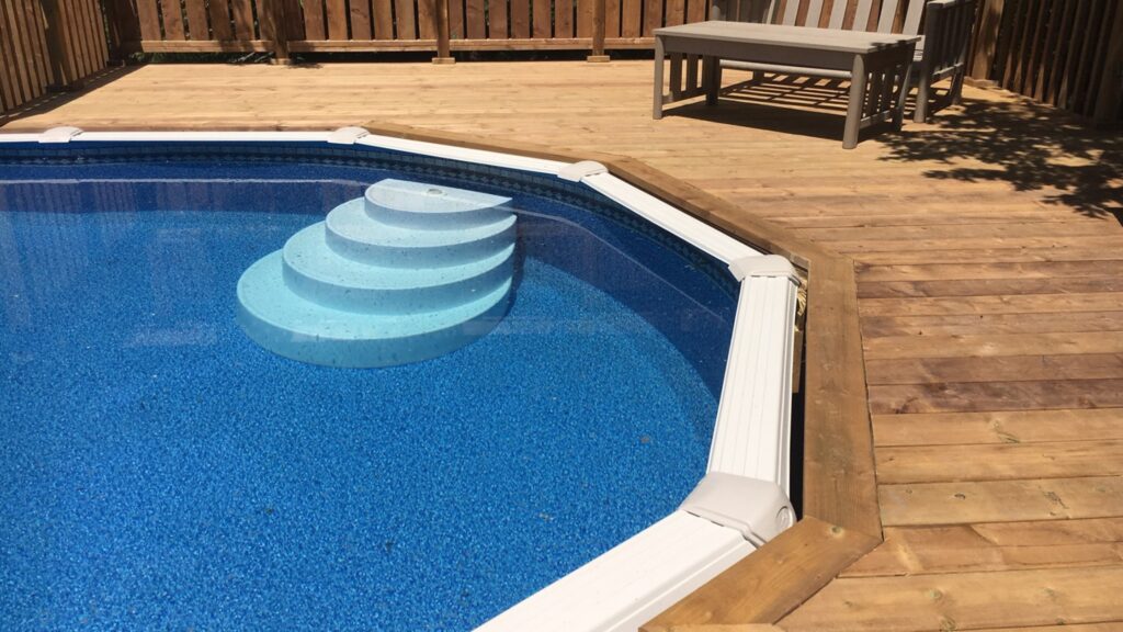Wooden pool deck close-up with blue steps, built-in bench, and seating area.