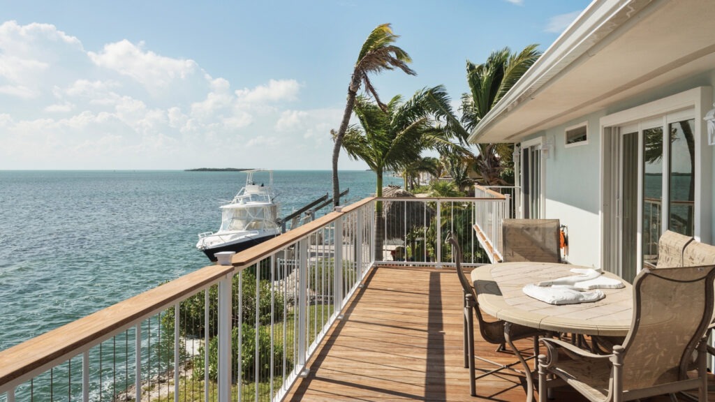 Coastal white cable railing deck overlooking blue ocean.