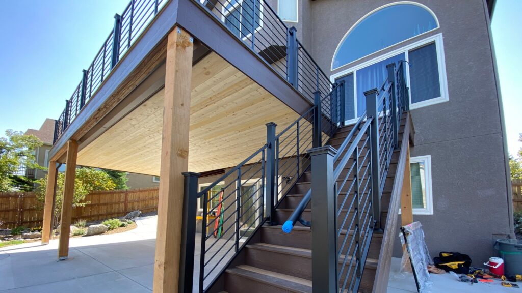 Contemporary black aluminum horizontal stair railing on modern two-story composite deck design.