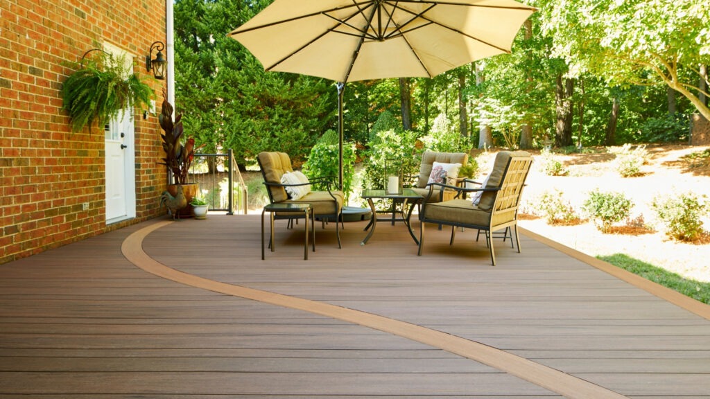 Curved TimberTech Vintage Mahogany and Cypress deck with tan furniture and umbrella.
