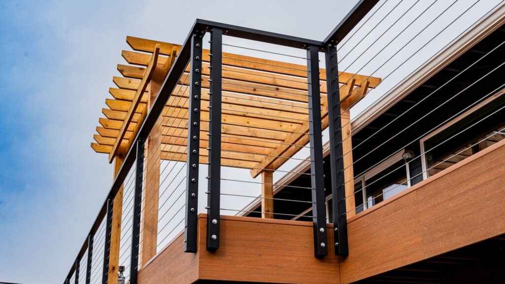 Contemporary deck with pergola and black cable railing, mixed material outdoor design example.