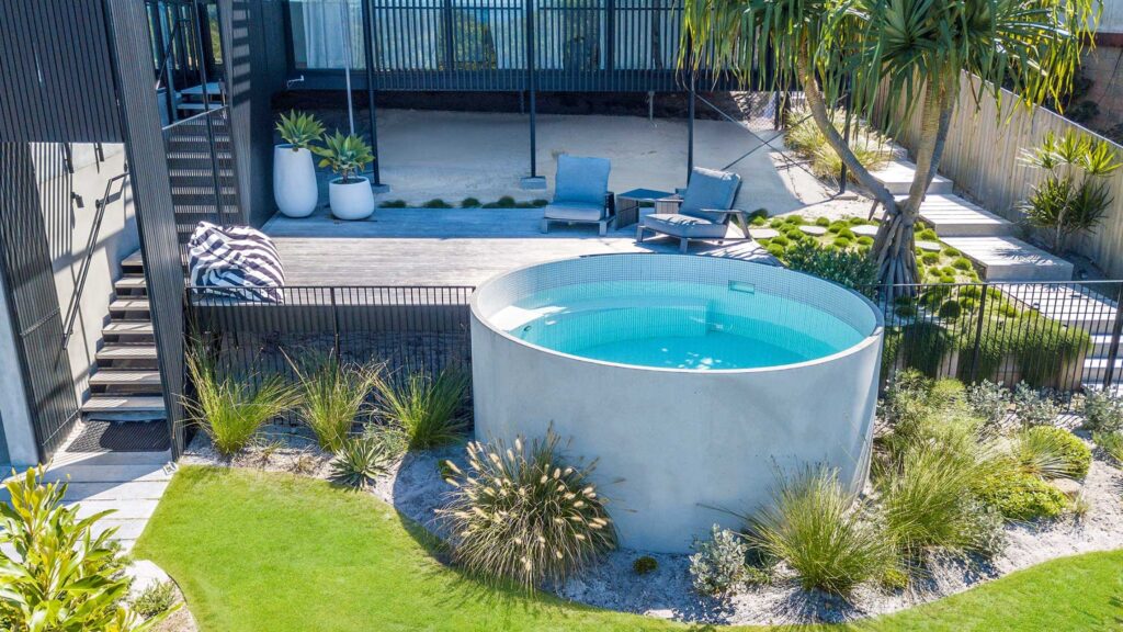 Elevated circular above-ground pool with modern deck and landscaped garden.