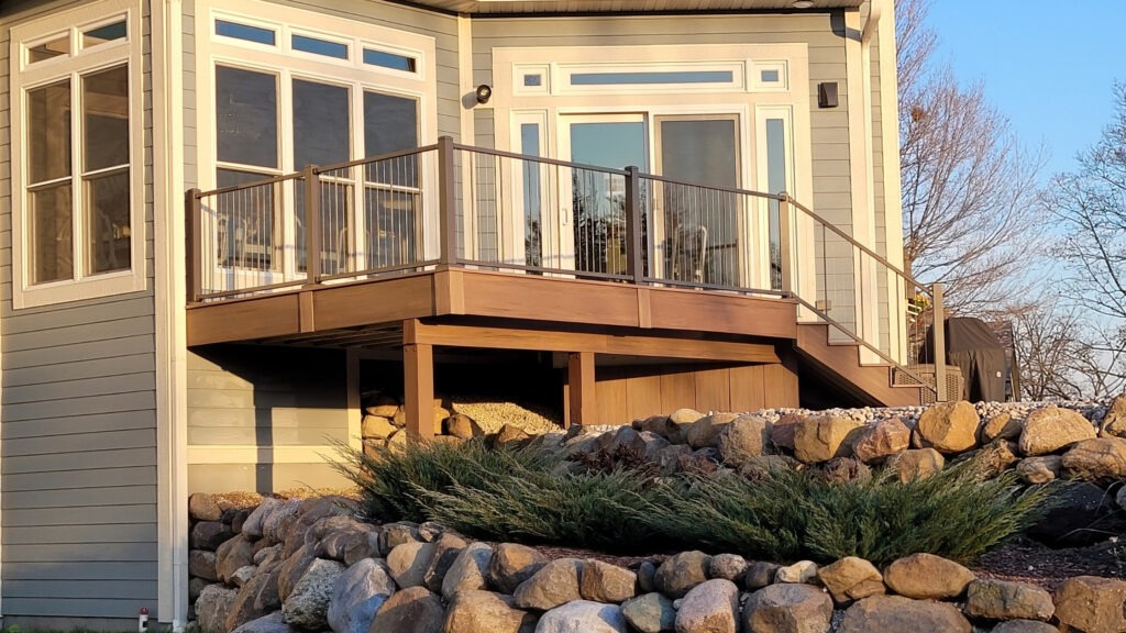 Elevated brown deck with gray posts and horizontal cable railing at sunset.