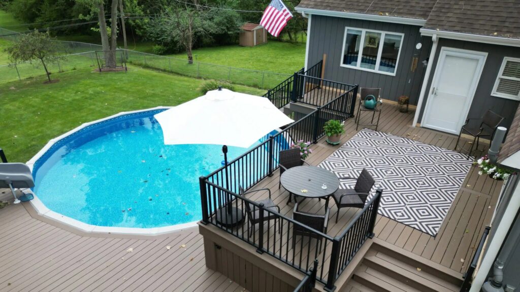 Elevated round above-ground pool deck with black railings and seating area.